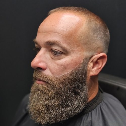 Man with a short faded cut and a full, thick beard trimmed and shaped