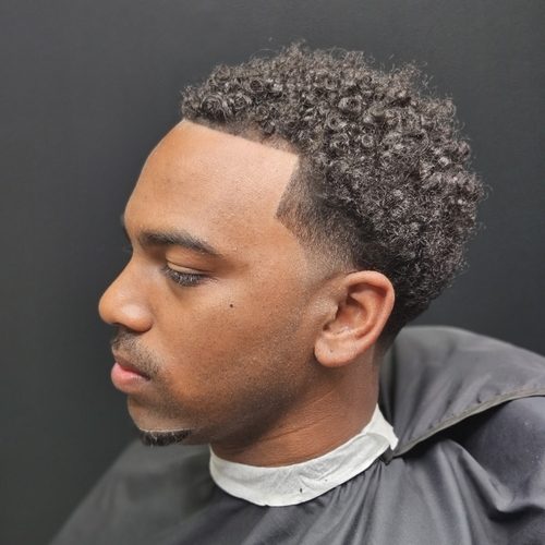 Young man in profile with a curly top, a temple fade and a clean line-up