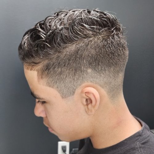 Boy with a wavy, textured top swept forward and a skin fade on the sides
