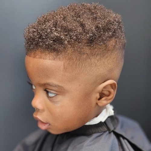 Little boy with a curly top, a high fade and a sharp edge, seen from the side
